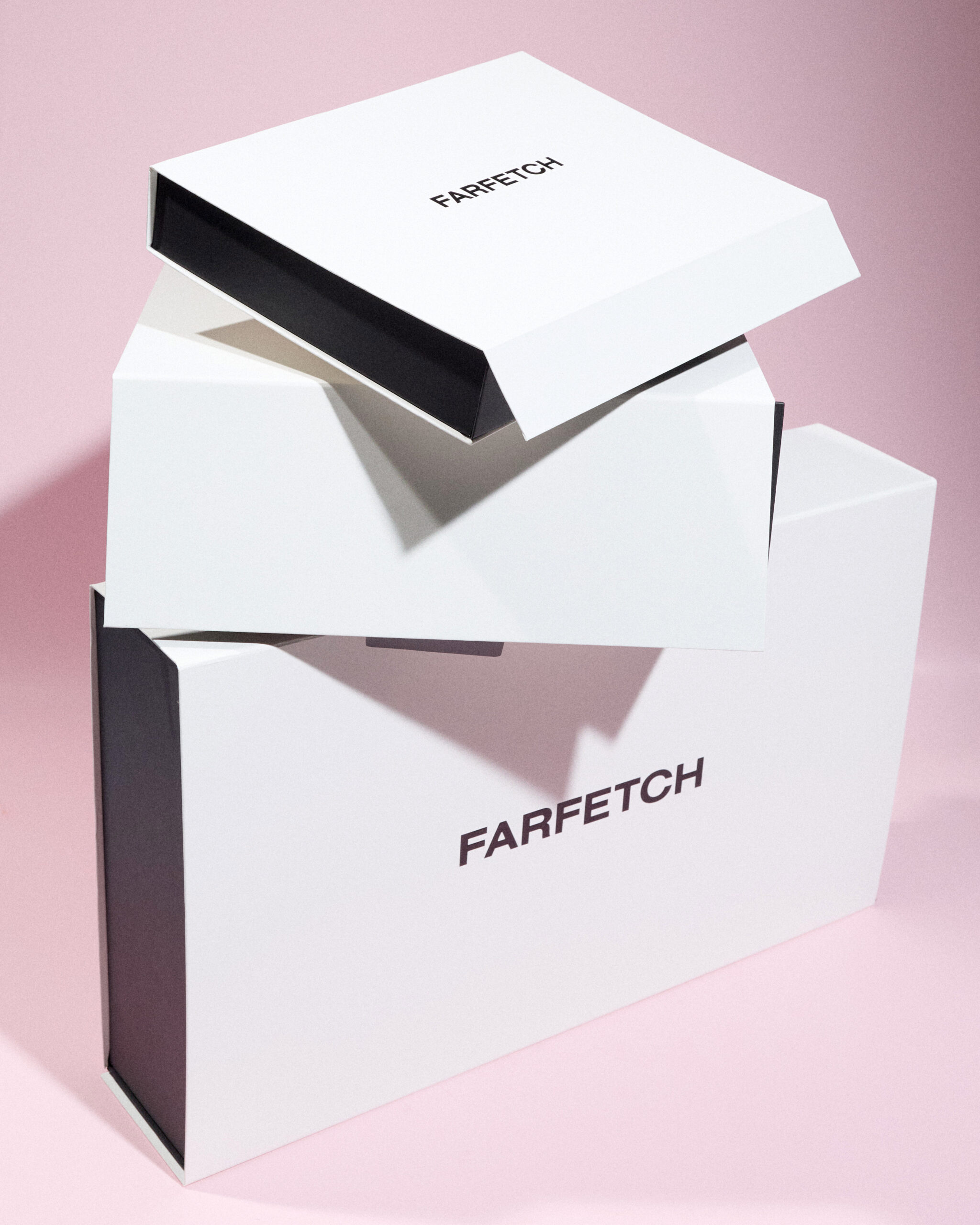 Redesigned FARFETCH Holiday 2026 packaging: black and white gift boxes against a pink background